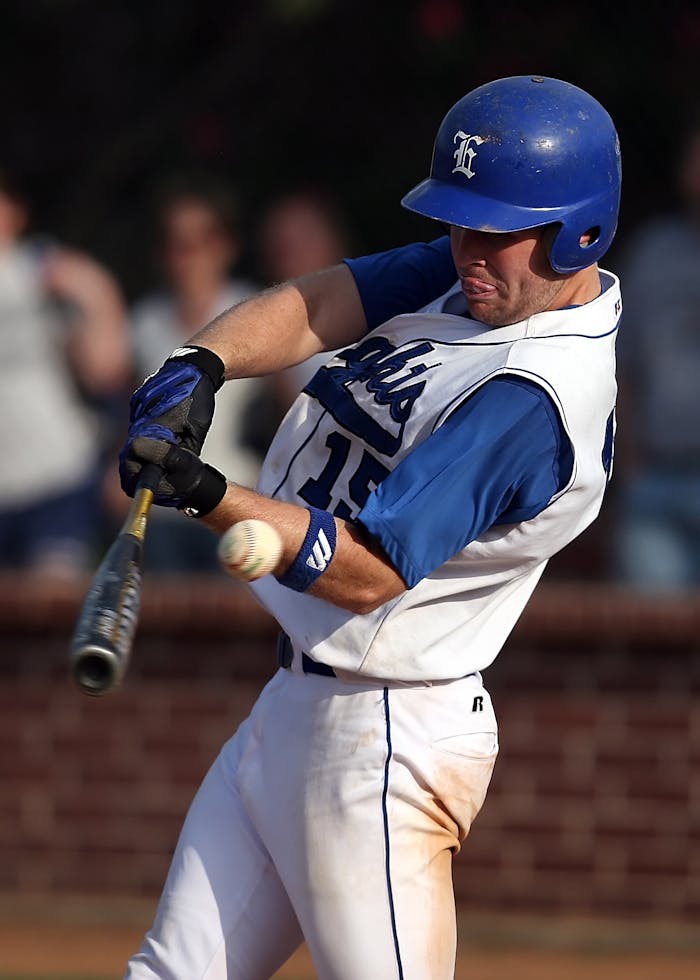Dynamic shot of a baseball player swinging a bat during a game, wearing a blue and white uniform.