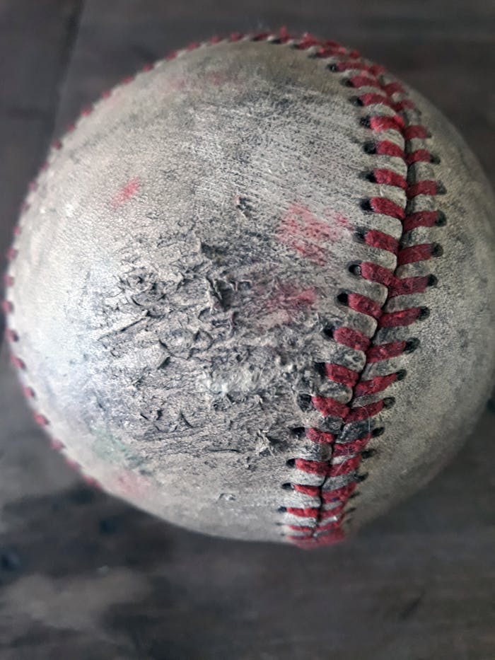 A close-up of an old, rugged baseball with detailed stitching.
